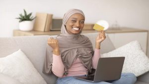 happy-black-woman-in-hijab-holding-credit-card